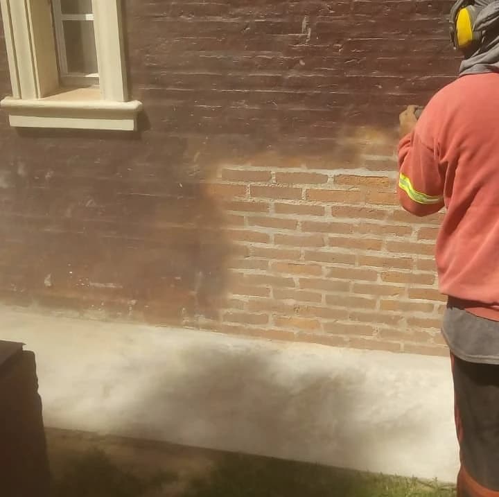 Arenado de una pared de ladrillo a la vista: la mitad ya limpia, la mitad todavía con la suciedad vieja